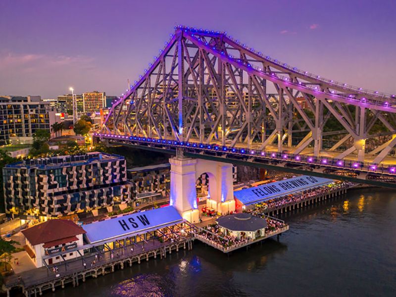 Howard Smith Wharves underneath Story Bridge lit up with purple lights with Felons Brewery busy with people below